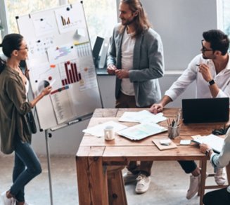 collaborateurs en présentation dans une entreprise autour d’une table avec un tableau blanc