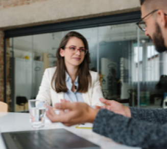 Jeune femme qui passe un entretien d’embauche face à un recruteur dans un bureau avec un ordinateur portable