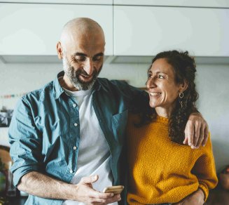 Un couple souriant consultant ses dépenses de santé sur un téléphone pour mieux gérer son budget santé