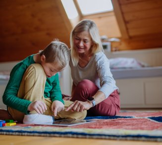 Personne retraitée accompagnant un enfant de sa famille lors d'une activité à domicile.