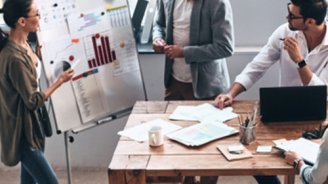 collaborateurs en présentation dans une entreprise autour d’une table avec un tableau blanc