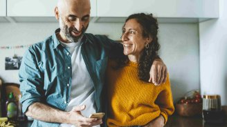 Un couple souriant consultant ses dépenses de santé sur un téléphone pour mieux gérer son budget santé
