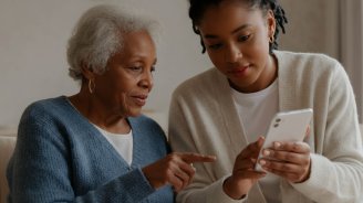Femme senior accompagnée par sa petite-fille pour activer ou consulter sa carte Vitale numérique sur un téléphone portable 