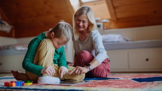 Personne retraitée accompagnant un enfant de sa famille lors d'une activité à domicile.