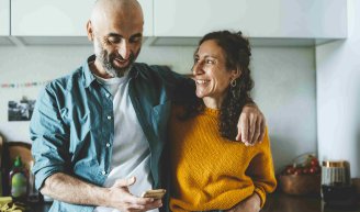 Un couple souriant consultant ses dépenses de santé sur un téléphone pour mieux gérer son budget santé