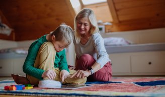 Personne retraitée accompagnant un enfant de sa famille lors d'une activité à domicile.